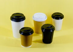 Five cups with lids in different colours on a yellow background