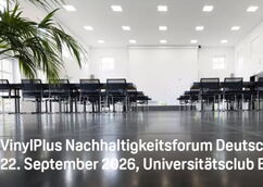 Close-up of a bright, modern seminar room with rows of black chairs and tables, palm trees to the left and right, with a projected white text slide reading ‘VinylPlus Sustainability Forum Germany 22 September 2026, University Club Bonn’