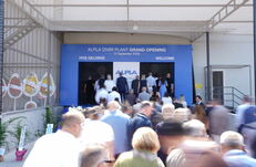 Menschenmenge betritt einen Eingang mit blauem Banner, auf dem 'ALPLA IZMIR PLANT GRAND OPENING 15 September 2026' steht
